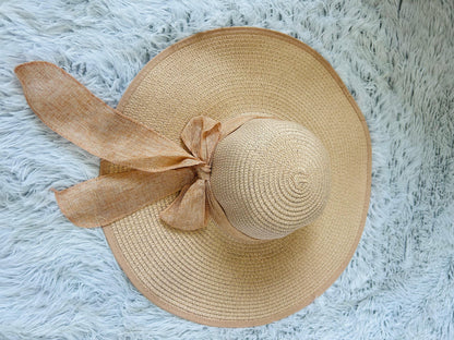 Beige straw hat with a bow on a fluffy white surface