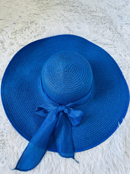 Blue straw hat with a ribbon on a textured white surface