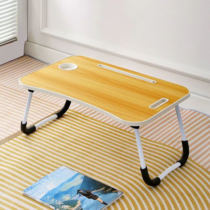 Foldable wooden desk on a striped rug with a magazine underneath