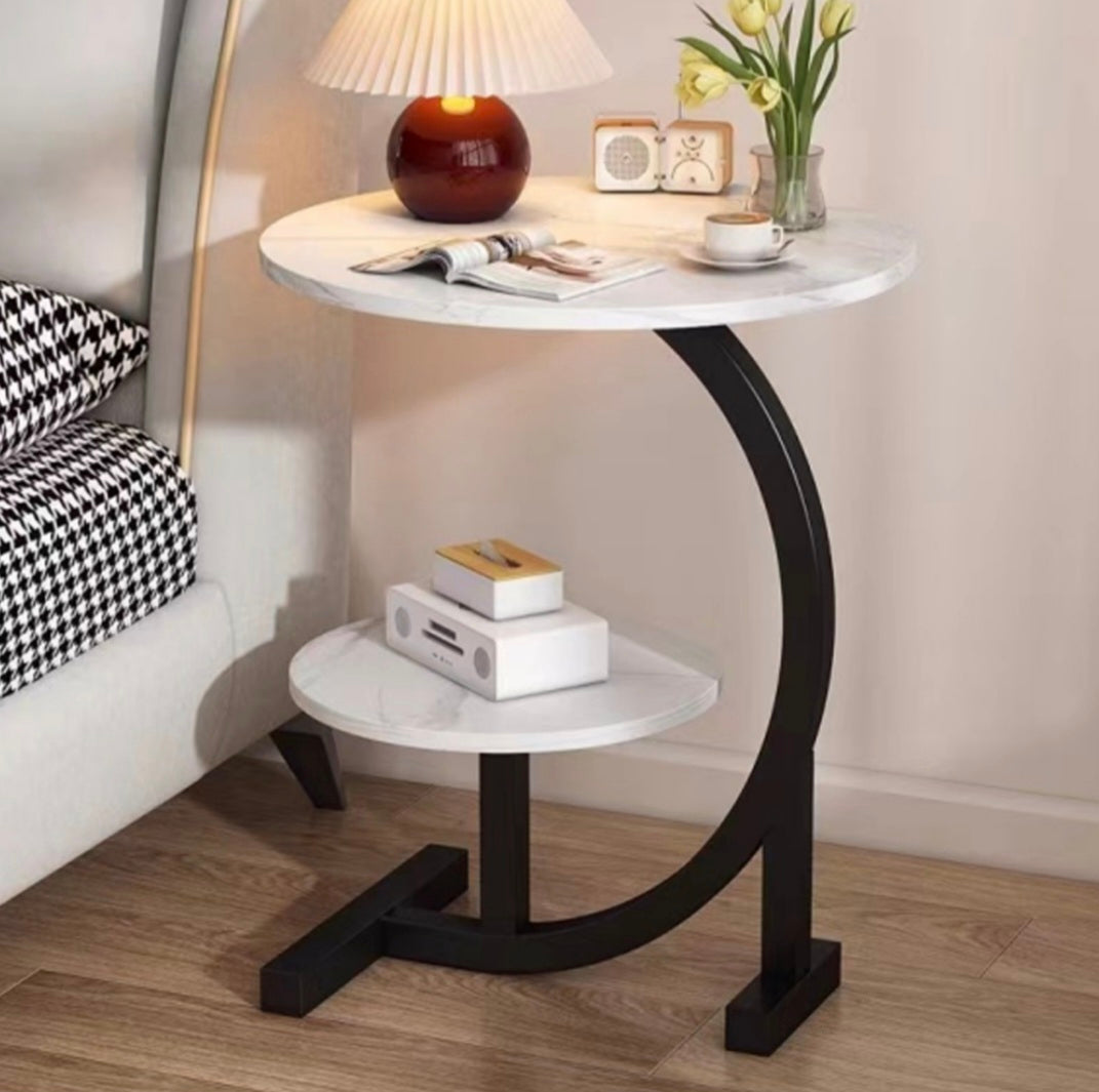 Small round marble top table with black curved legs in a room setting.