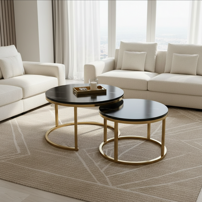 Two round nesting coffee tables with black tops and gold metal frames, styled in a modern living room with cream sofas and a beige rug.