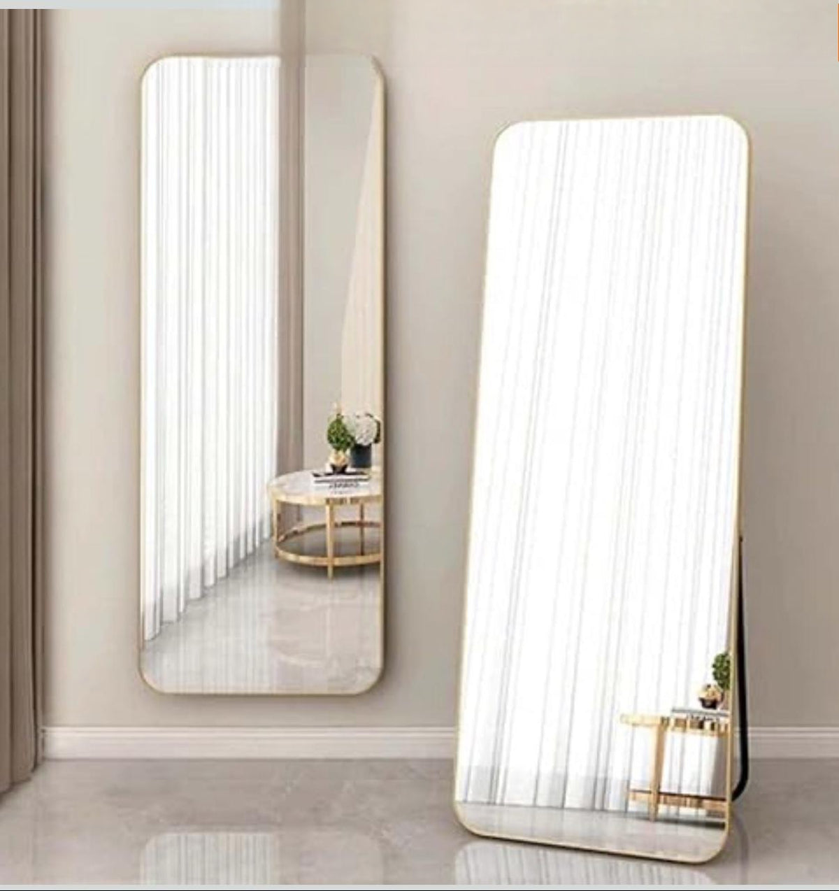 Two large floor mirrors reflecting a room with a table and decor.