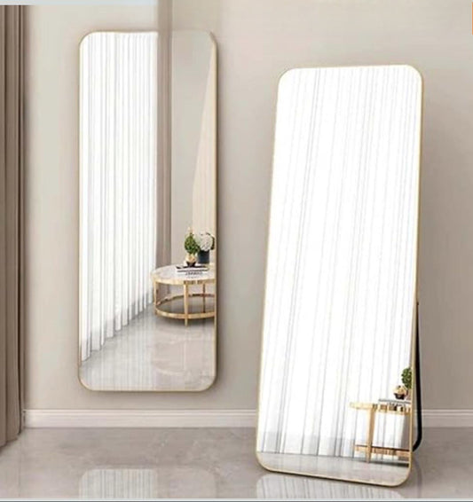 Two large floor mirrors reflecting a room with a table and decor.
