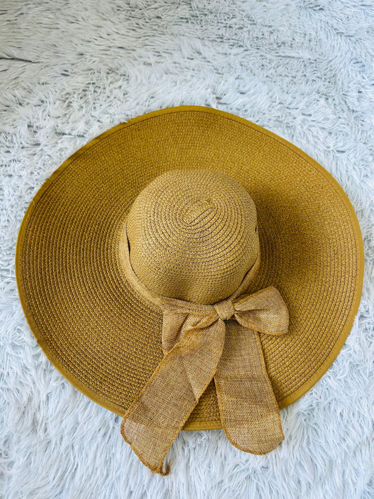 Khaki straw hat with a bow on a white textured surface