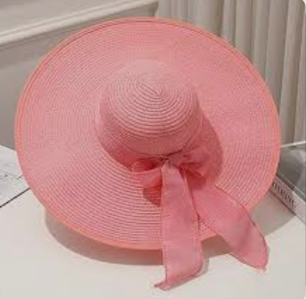 Pink straw hat with a bow on a white surface
