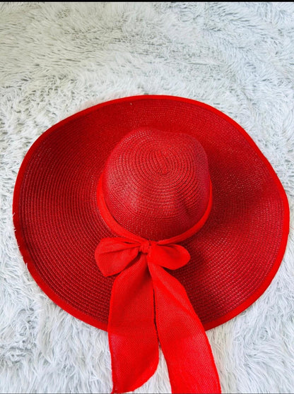Red straw hat with a bow on a white textured surface