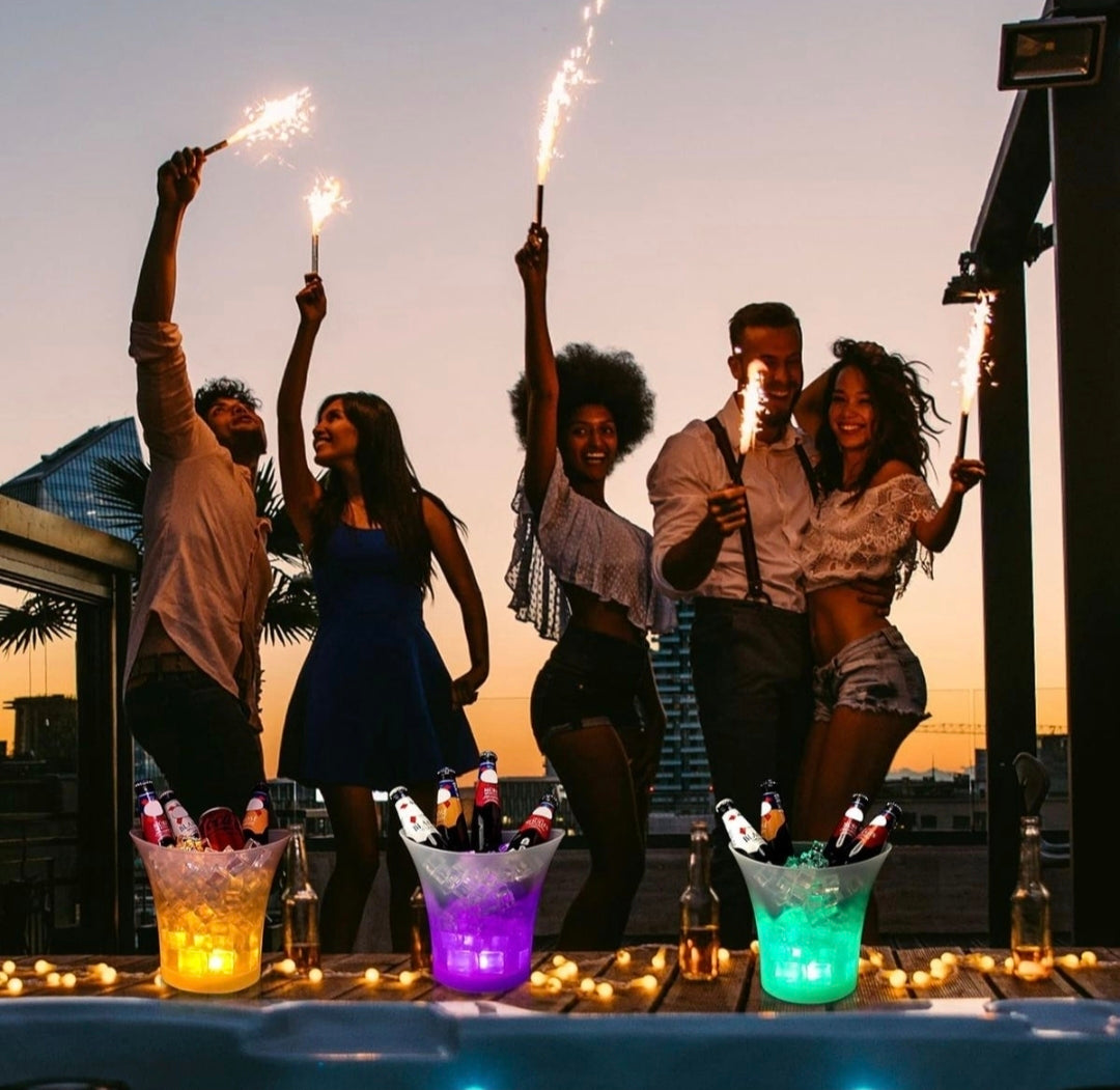 Group of people celebrating with sparklers on a rooftop at sunset.