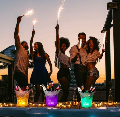Group of people celebrating with sparklers on a rooftop at sunset.