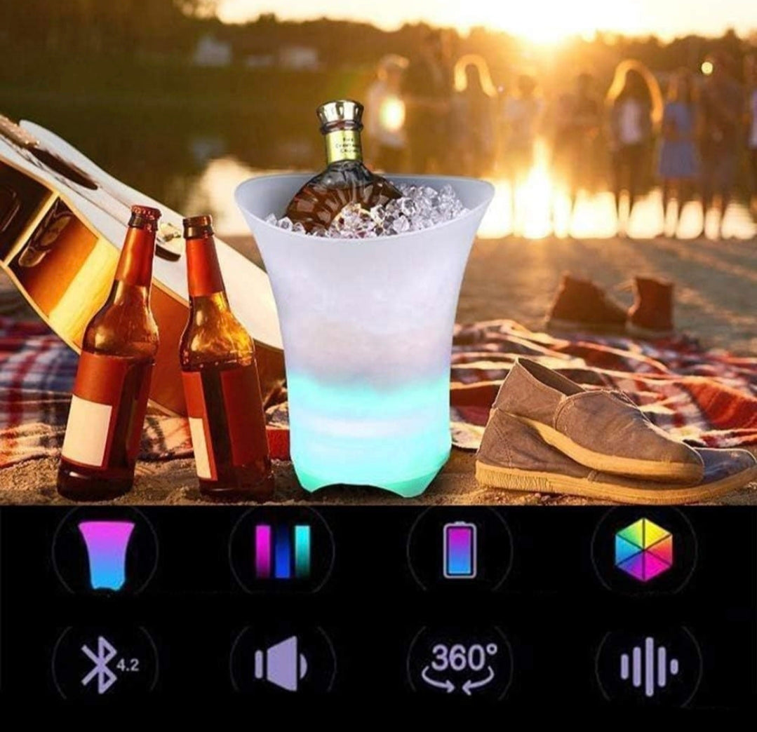 LED ice bucket with bottles on a beach at sunset, surrounded by people and a guitar.
