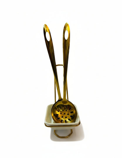 Gold-colored tea infuser with a white base on a white background