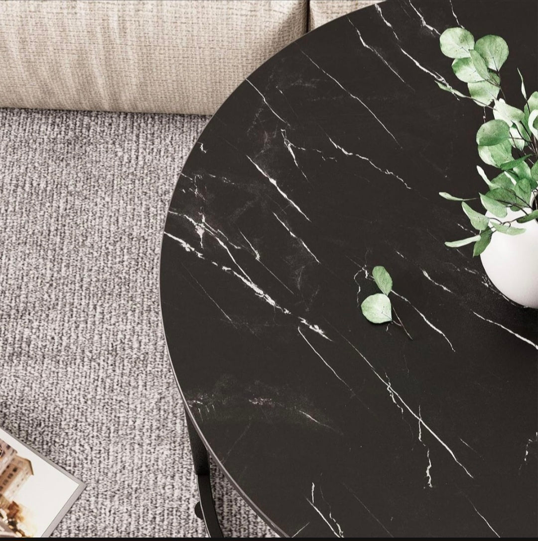 Round black marble table with a plant on a gray carpeted floor