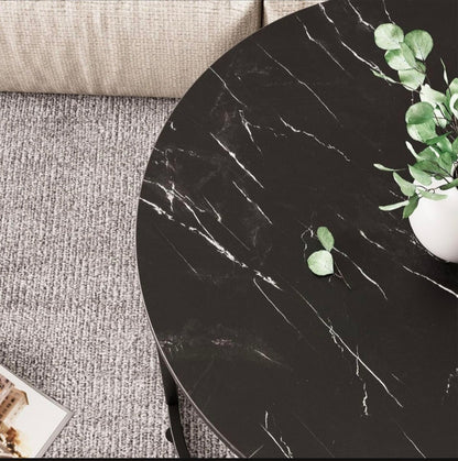 Round black marble table with a plant on a gray carpeted floor