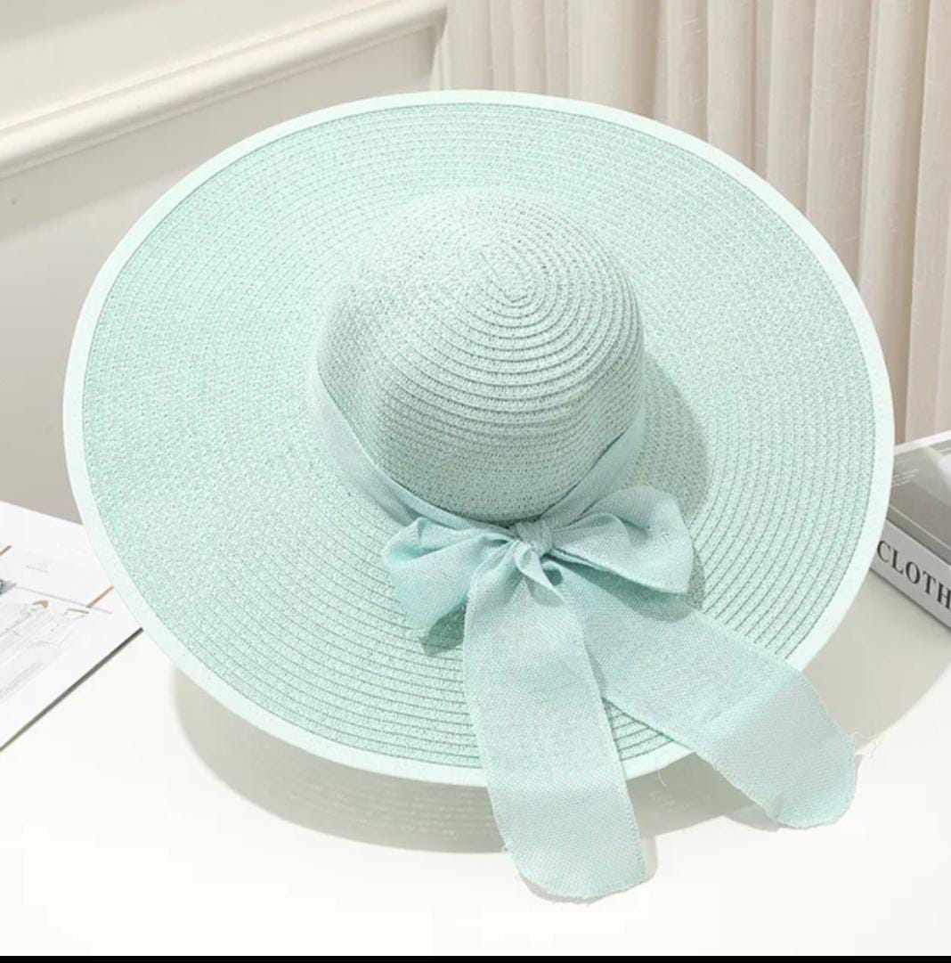 Teal  straw hat with a bow on a white surface