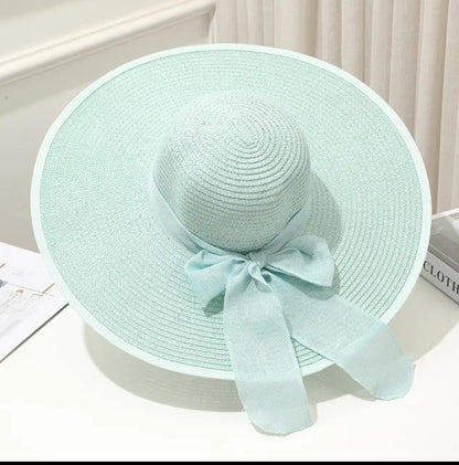 Teal  straw hat with a bow on a white surface