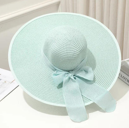 Teal straw hat with a bow on a white surface