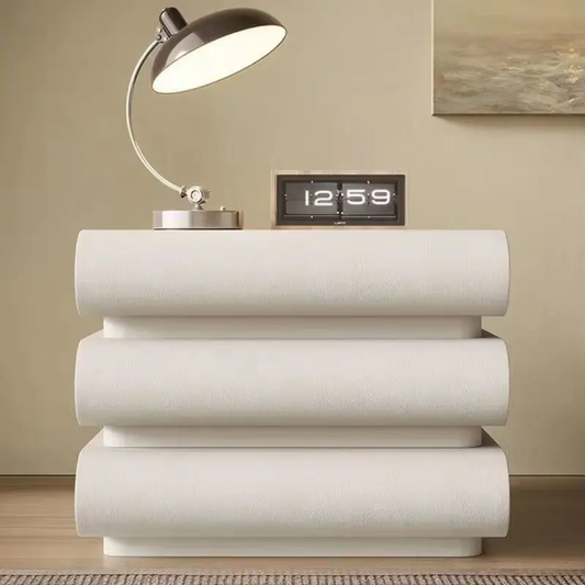 White decorative table with a lamp and digital clock on top against a beige wall.