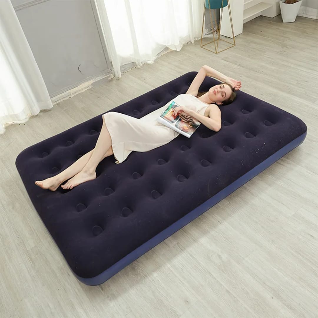 Woman lying on an inflatable mattress in a room with curtains and a table.