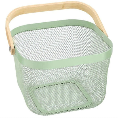 A square metal mesh basket in a light sage green color, featuring a natural light wood handle and a matching green metal rim, shown on a plain white background.