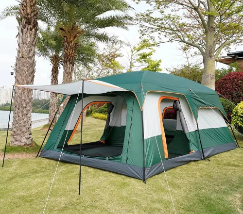 Green camping tent with attached porch on grassy area with trees and water in the background